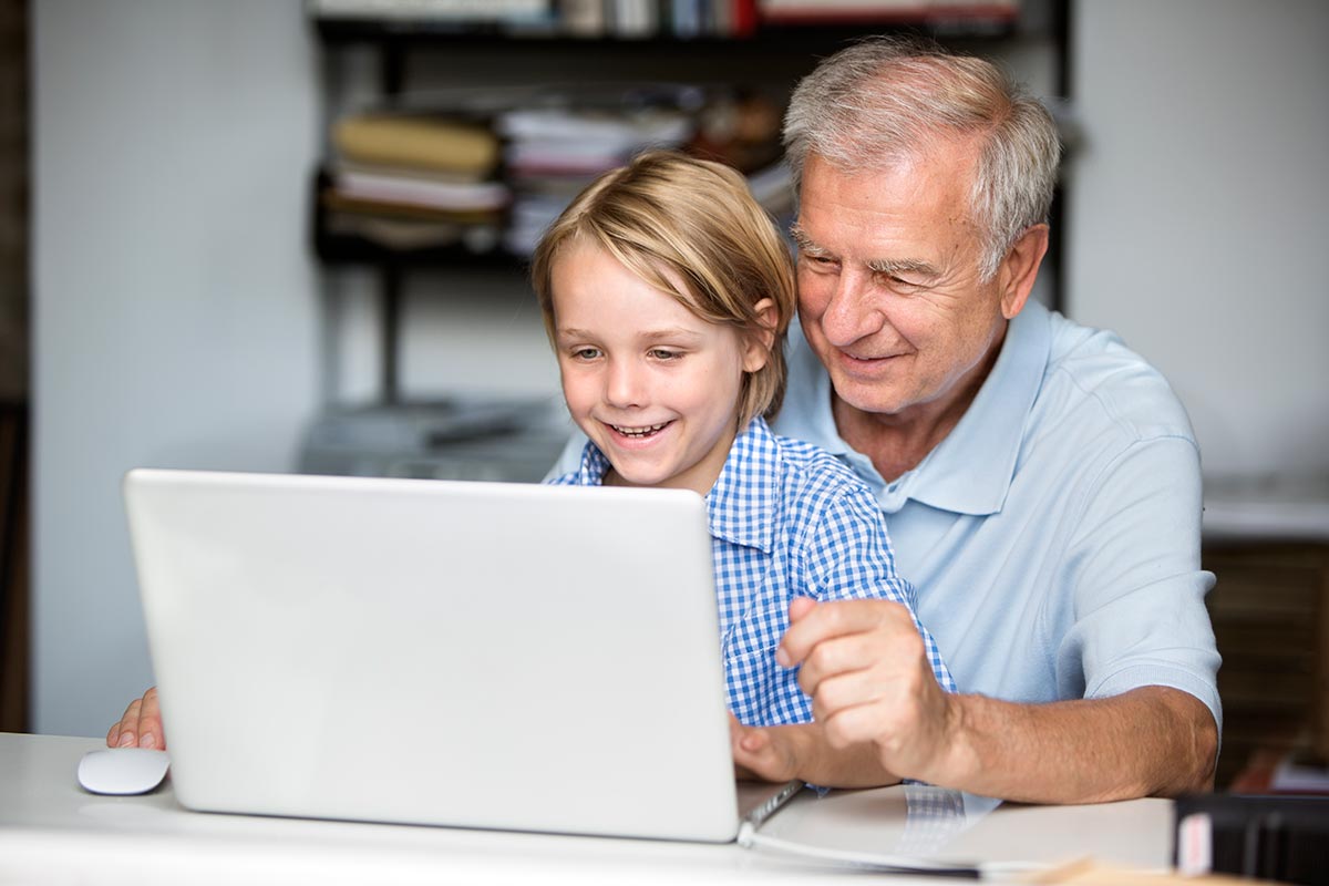 Junge zeigt seinem Großvater den Umgang mit dem Laptop